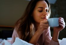 mujer sonriente disfrutando una bebida caliente