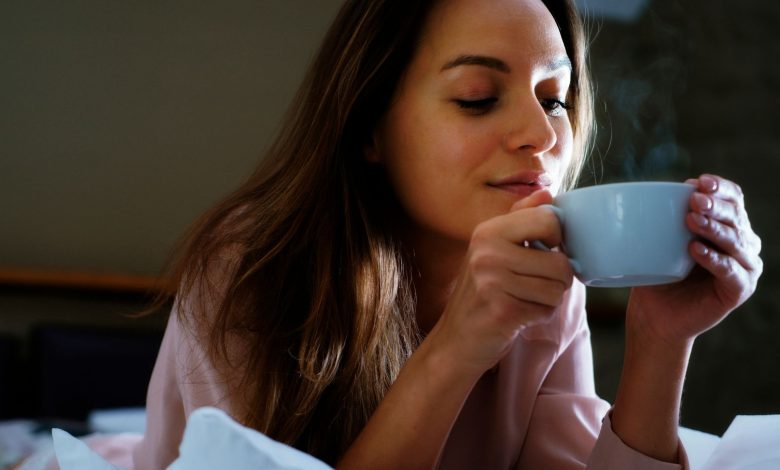 mujer sonriente disfrutando una bebida caliente